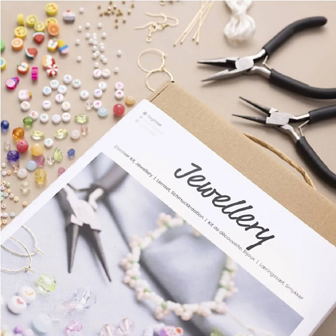 Overzicht van de creativ company sieraden knutselset met diverse kralen, tangen en de handleiding.