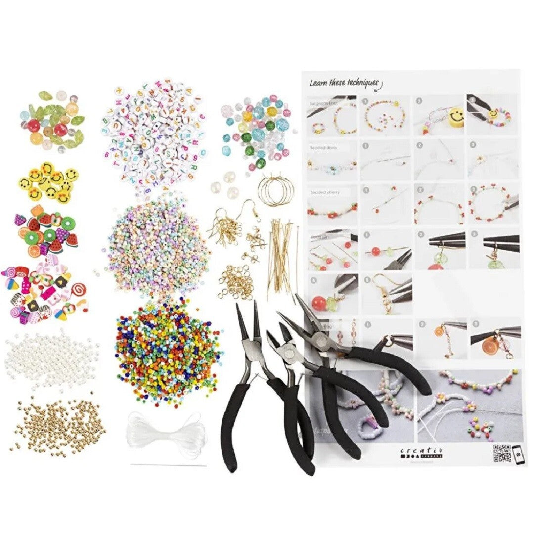 Alle onderdelen van de creativ company sieraden knutselset, inclusief diverse kralen, metalen onderdelen, drie tangen en een instructievel.