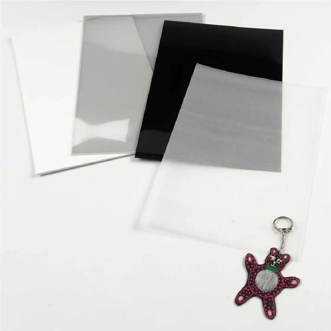 Creativ Company krimpfolie vellen in wit, grijs, zwart en transparant, met een afgewerkte teddybeer sleutelhanger.