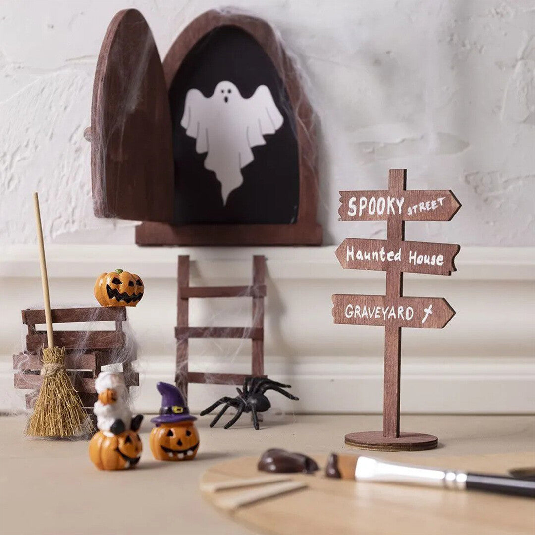 Een donkere Creativ Company miniatuurdeur in een Halloween-decoratie met een spook en pompoenen.