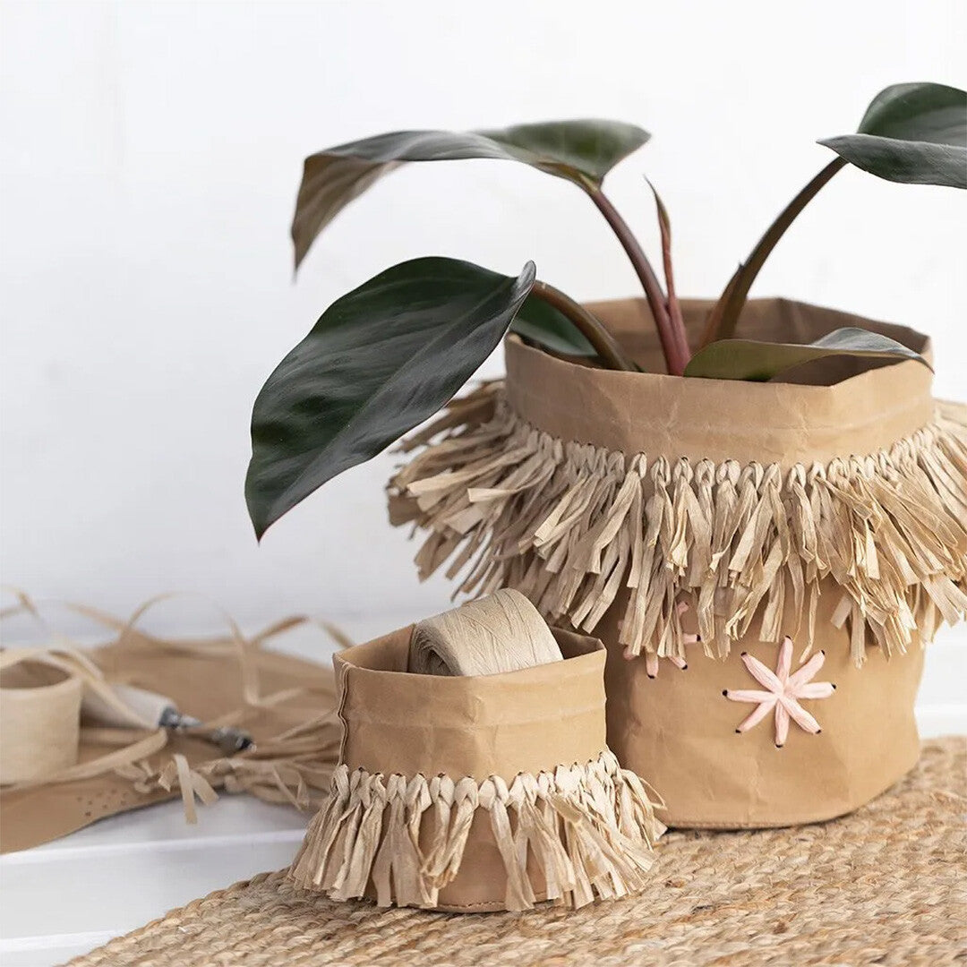 Twee decoratieve plantenpotten gemaakt van papier met raffia franjes, als voorbeeld van creaties met papiergaren.