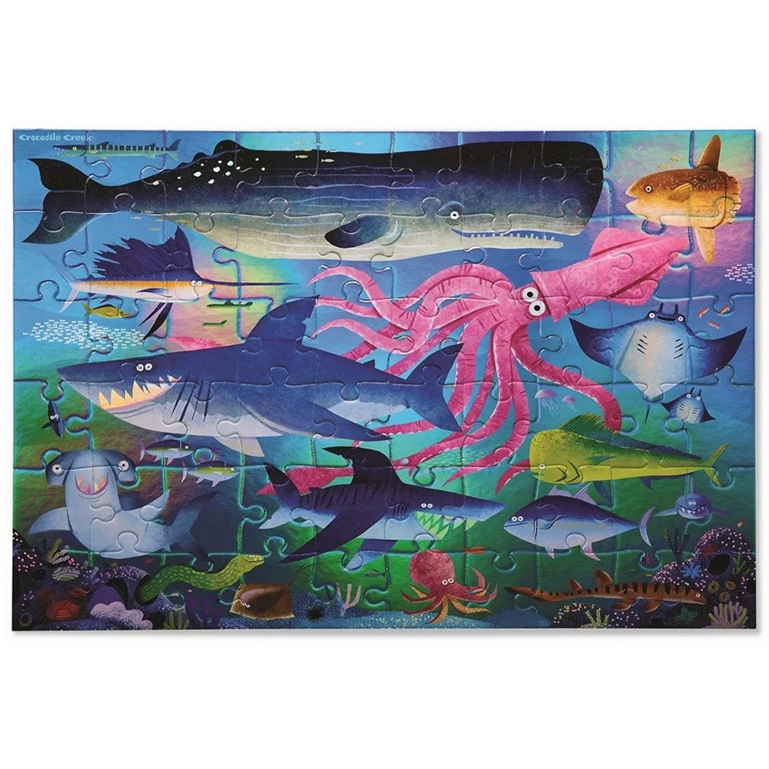 De complete Crocodile Creek Shimmering Sharks puzzel met 60 stukjes, waarop een walvis, inktvis, haaien en andere zeedieren te zien zijn.