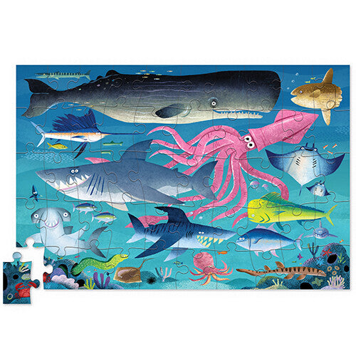 Voltooide haaienrif puzzel met diverse zeedieren zoals haaien, een walvis en een inktvis, met één los puzzelstukje.