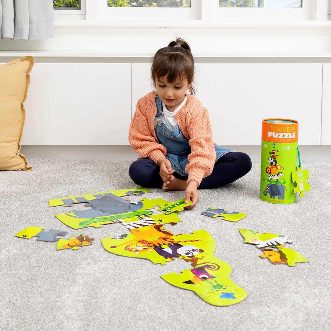 Een kind zit op de vloer en legt de Crocodile Creek vloerpuzzel met jungle dieren.