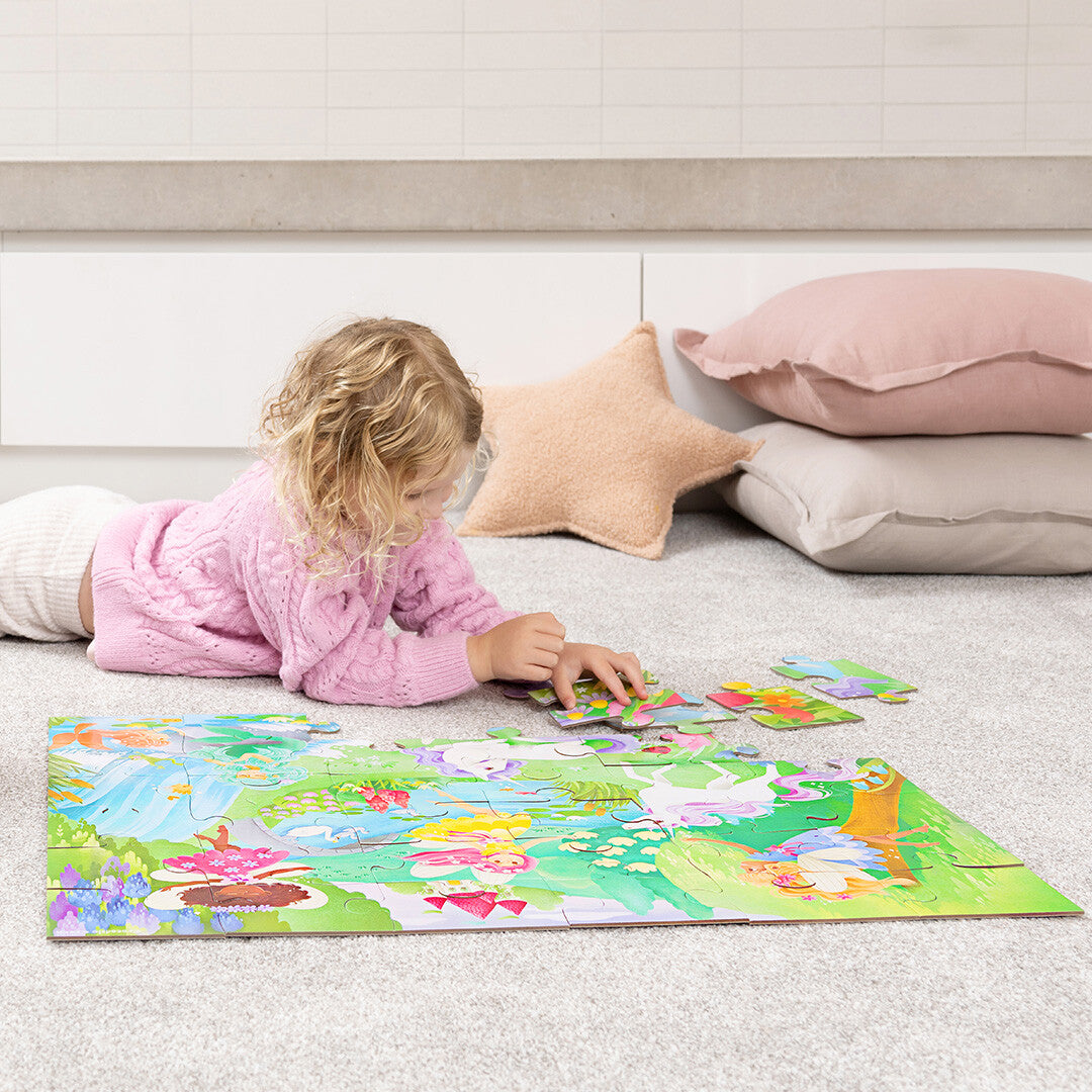 Een kind ligt op de buik en legt de Crocodile Creek vloerpuzzel met magische vriendjes.