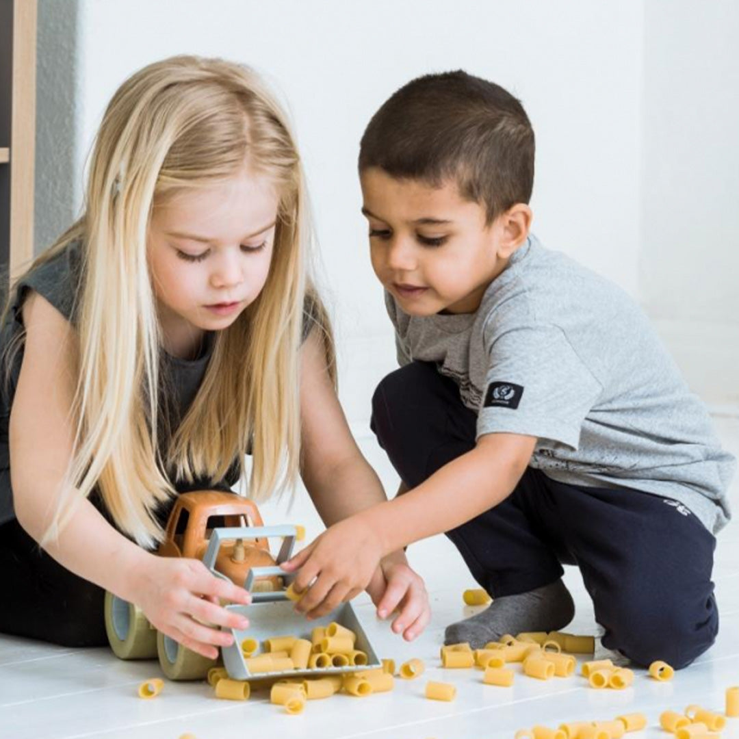 Twee kinderen spelen met de dantoy speelgoedtractor die gevuld is met pasta.
