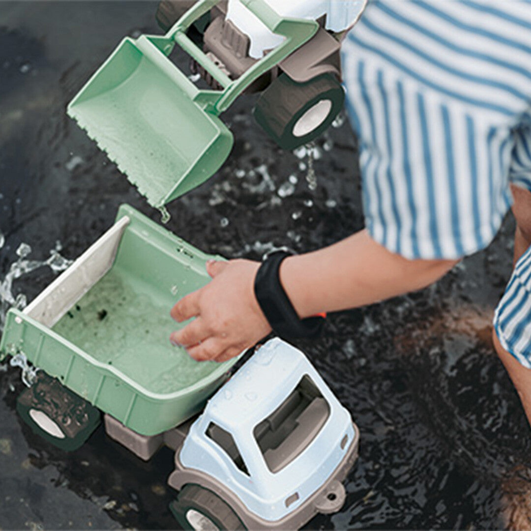 Een kind speelt met de dantoy speelgoedvrachtwagen in water.