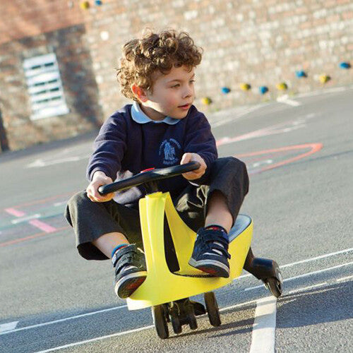 Een jongen rijdt op een gele Plasmacar didicar op een speelplaats.