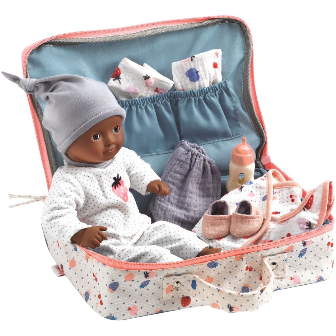 Djeco babypop met donkere huidskleur in een open koffer met stippenpatroon, omringd door babyaccessoires zoals kleding en een fles.