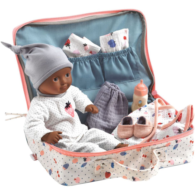 Djeco babypop met donkere huidskleur in een open koffer met stippenpatroon, omringd door babyaccessoires zoals kleding en een fles.