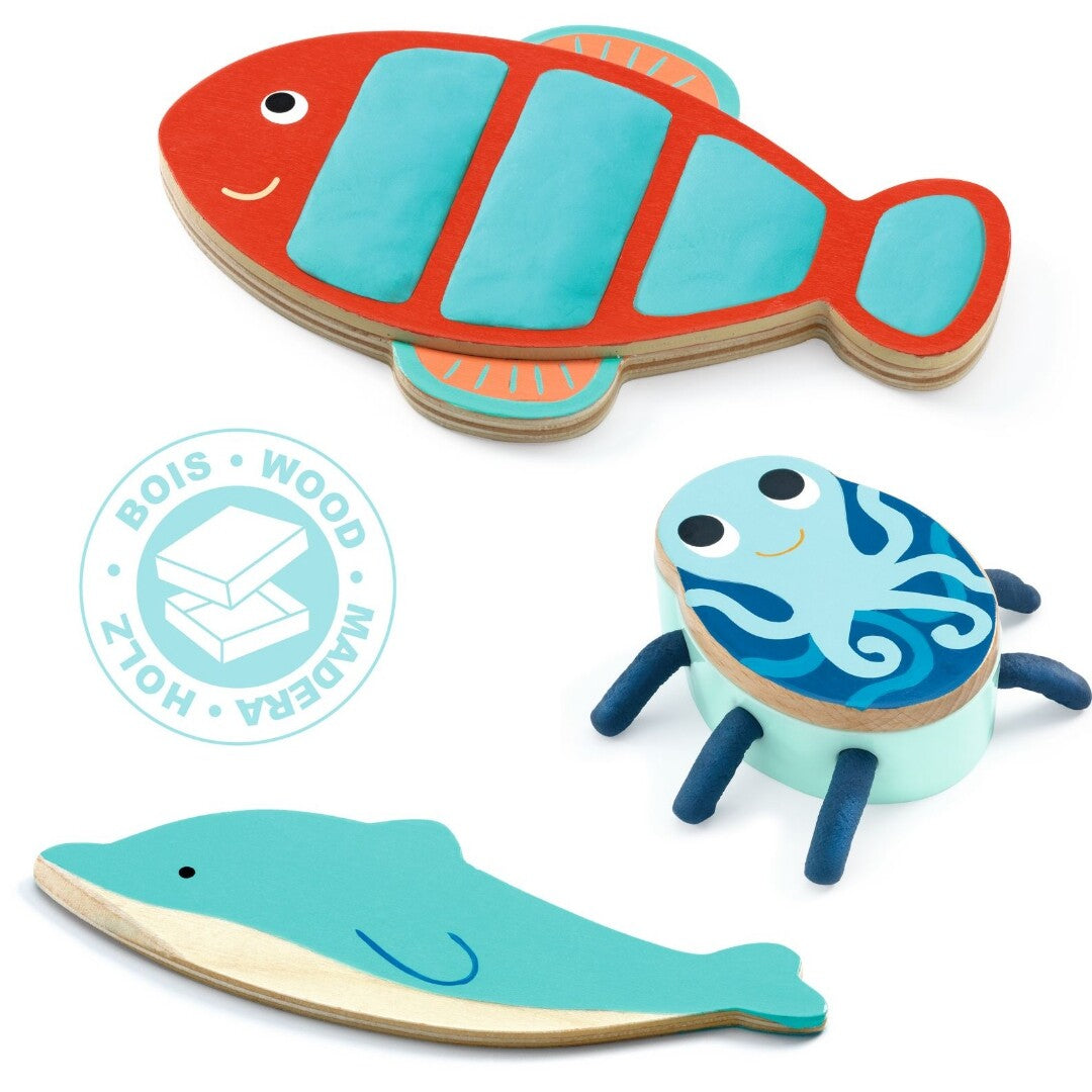 Drie houten zeedieren van de Djeco boetseerklei set: een rode vis, een blauwe dolfijn en een blauwe octopus.