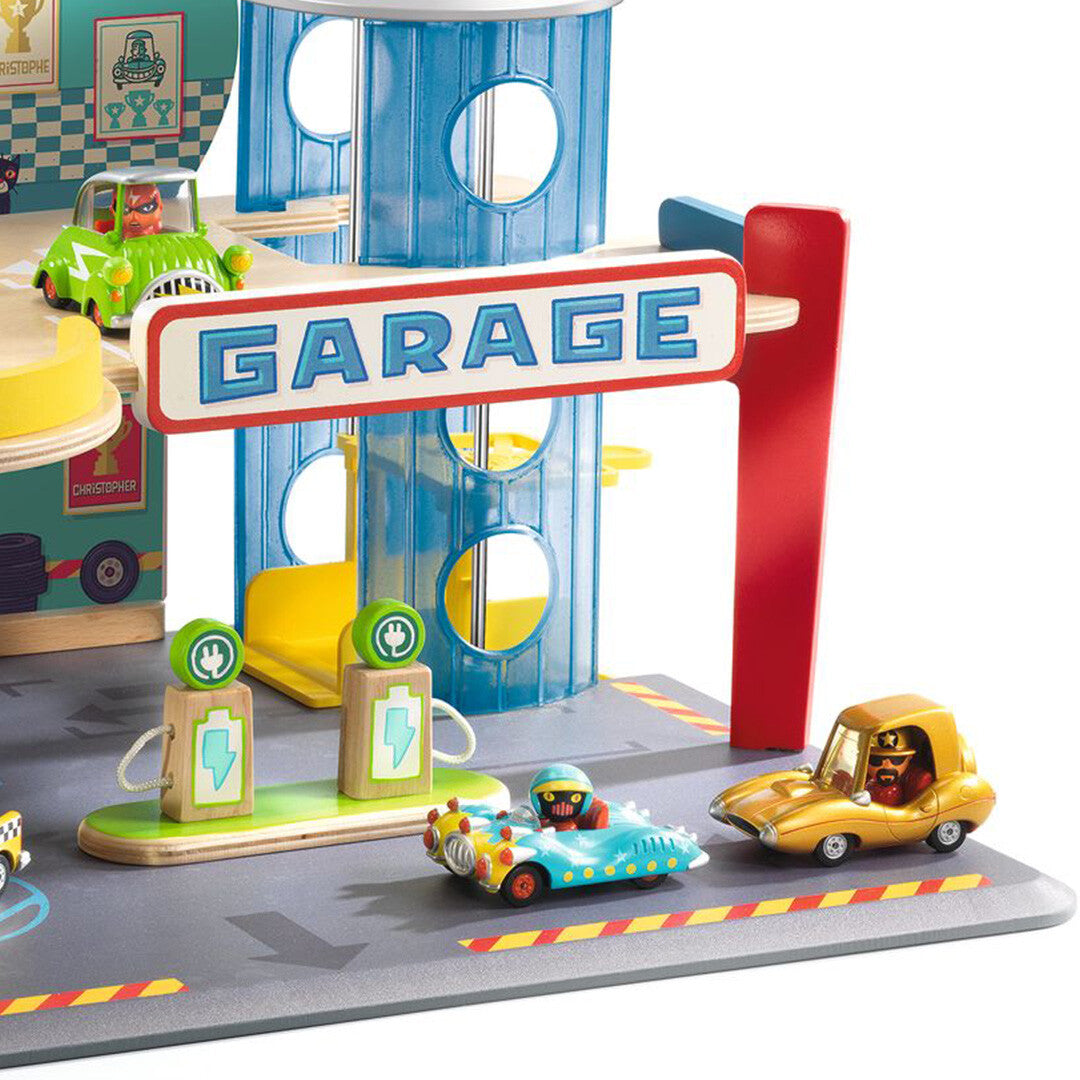 Detail van de Djeco Crazy Motors garage met het 'GARAGE' bord, een tankstation en drie speelgoedauto's.