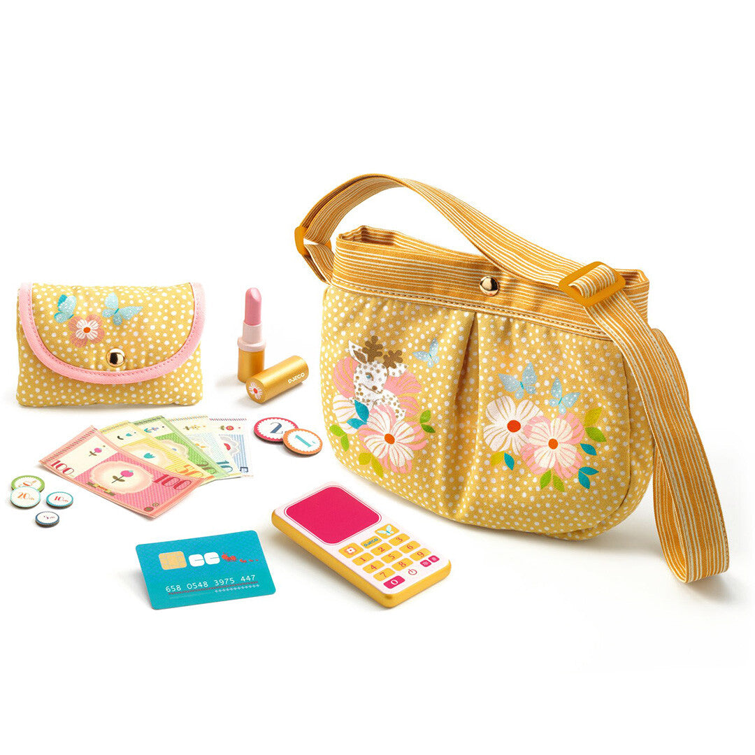 Djeco geel speelhandtasje met bloemen en een portemonnee, speelgeld, speelcreditcard, speeltelefoon en speellippenstift op een witte achtergrond.