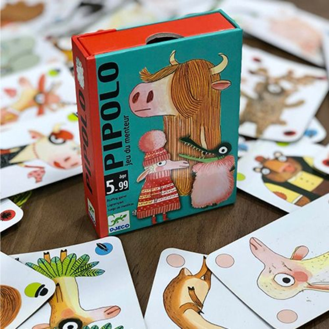 Djeco Pipolo blufspel kaartspel verpakking omringd door speelkaarten met dierenillustraties op een houten ondergrond.