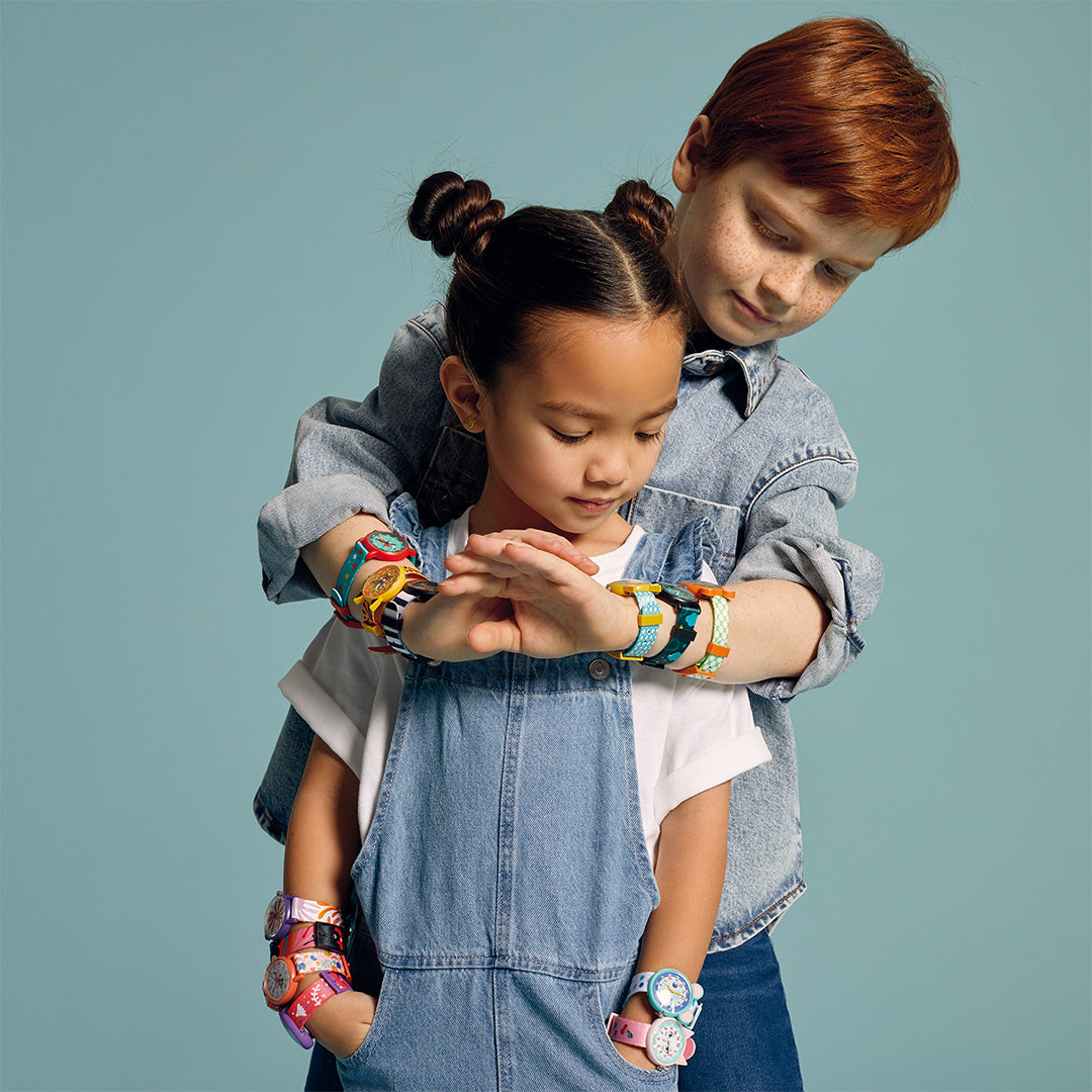 Twee kinderen met diverse kleurrijke Djeco kinderhorloges om hun polsen.