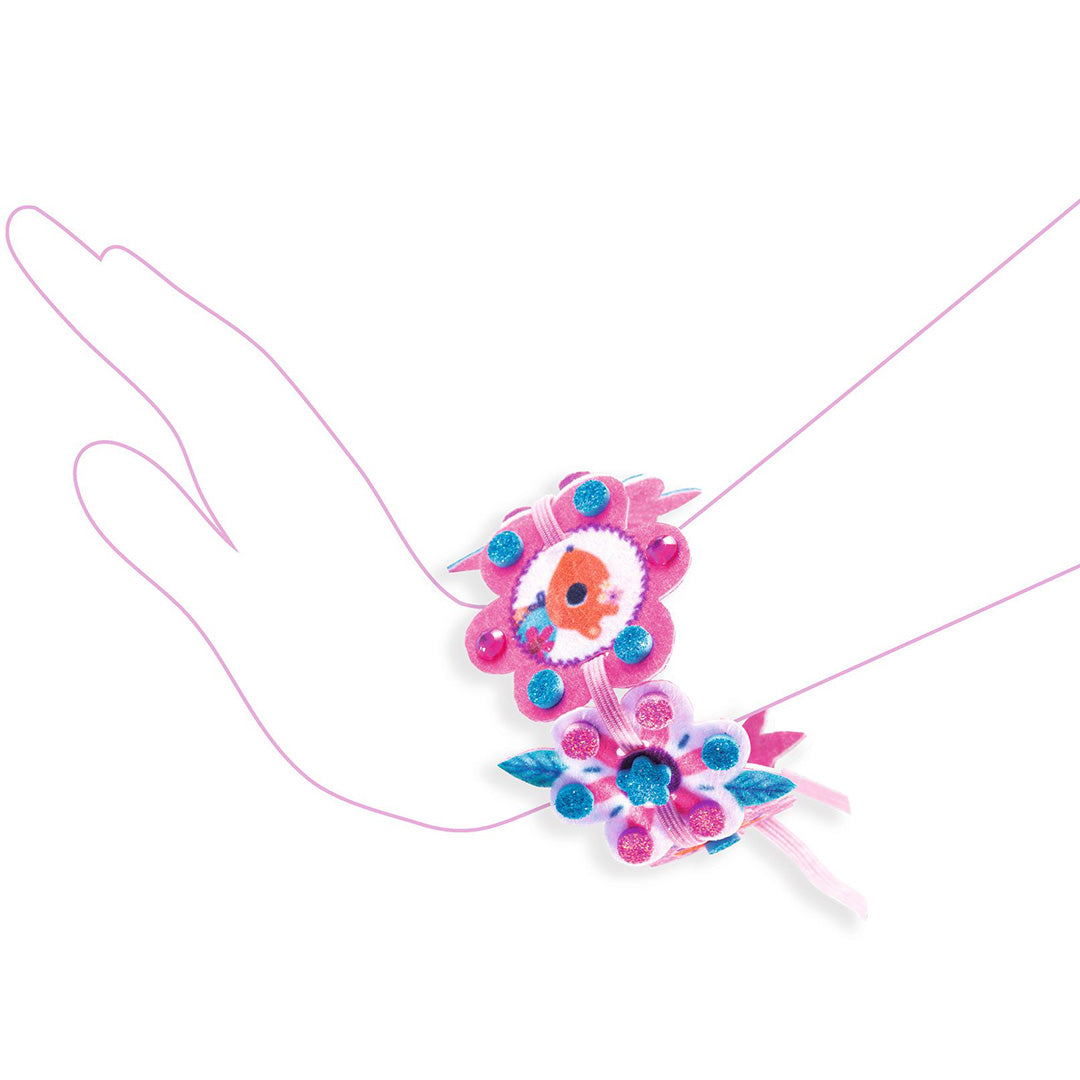 Infographic met een voorbeeld van een afgewerkt vilten armbandje met bloemen om een hand.
