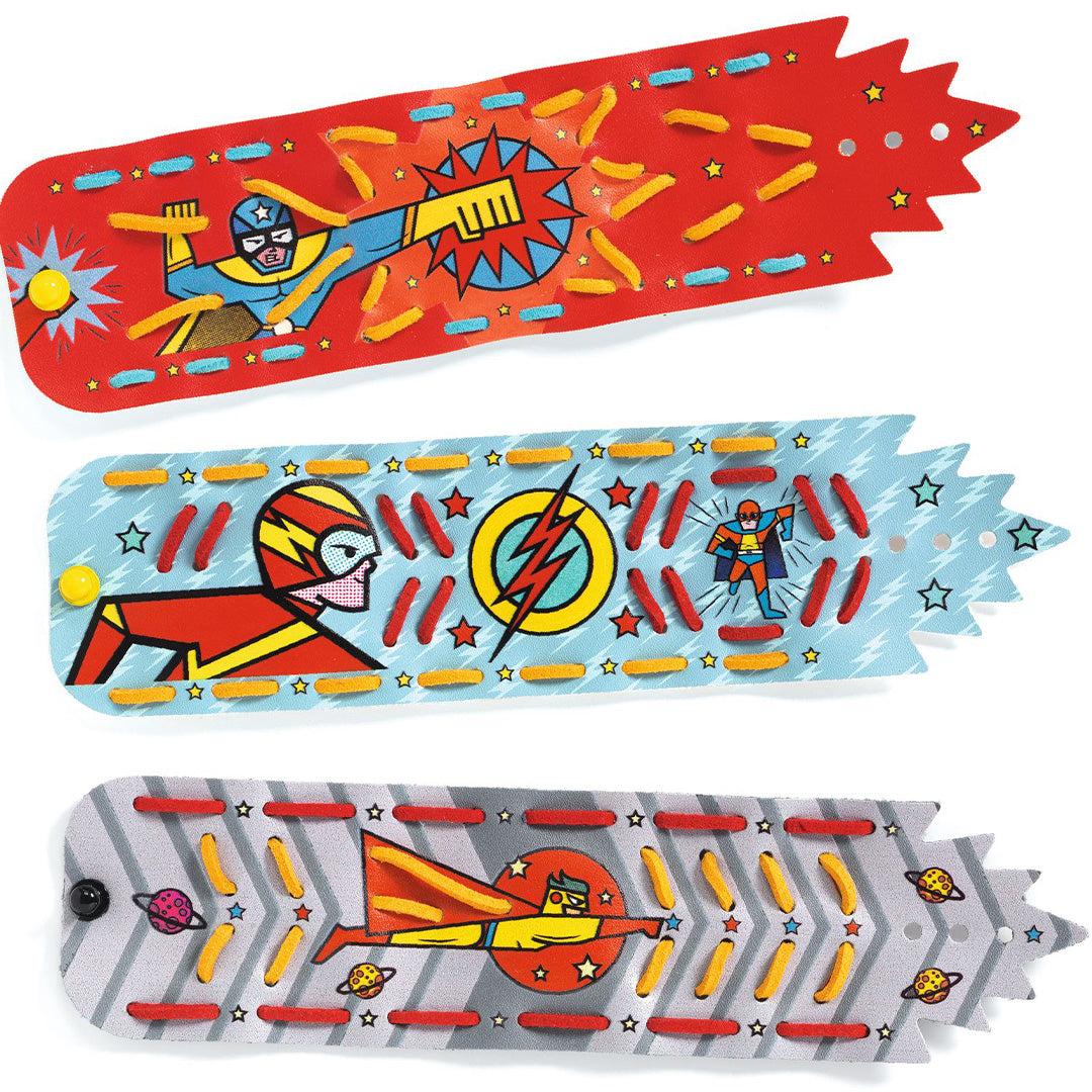 Drie onbewerkte superheldenarmbanden van de Djeco knutselset, met verschillende helden en patronen.