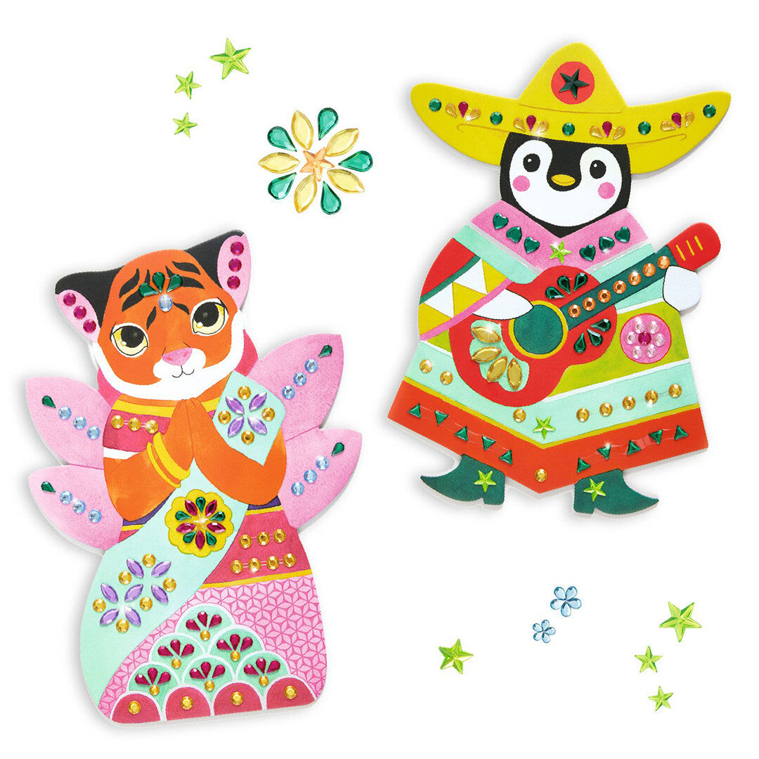 Twee versierde figuren van de knutselset: een tijger met vleugels en een pinguïn met sombrero en gitaar, omringd door glitterstenen.