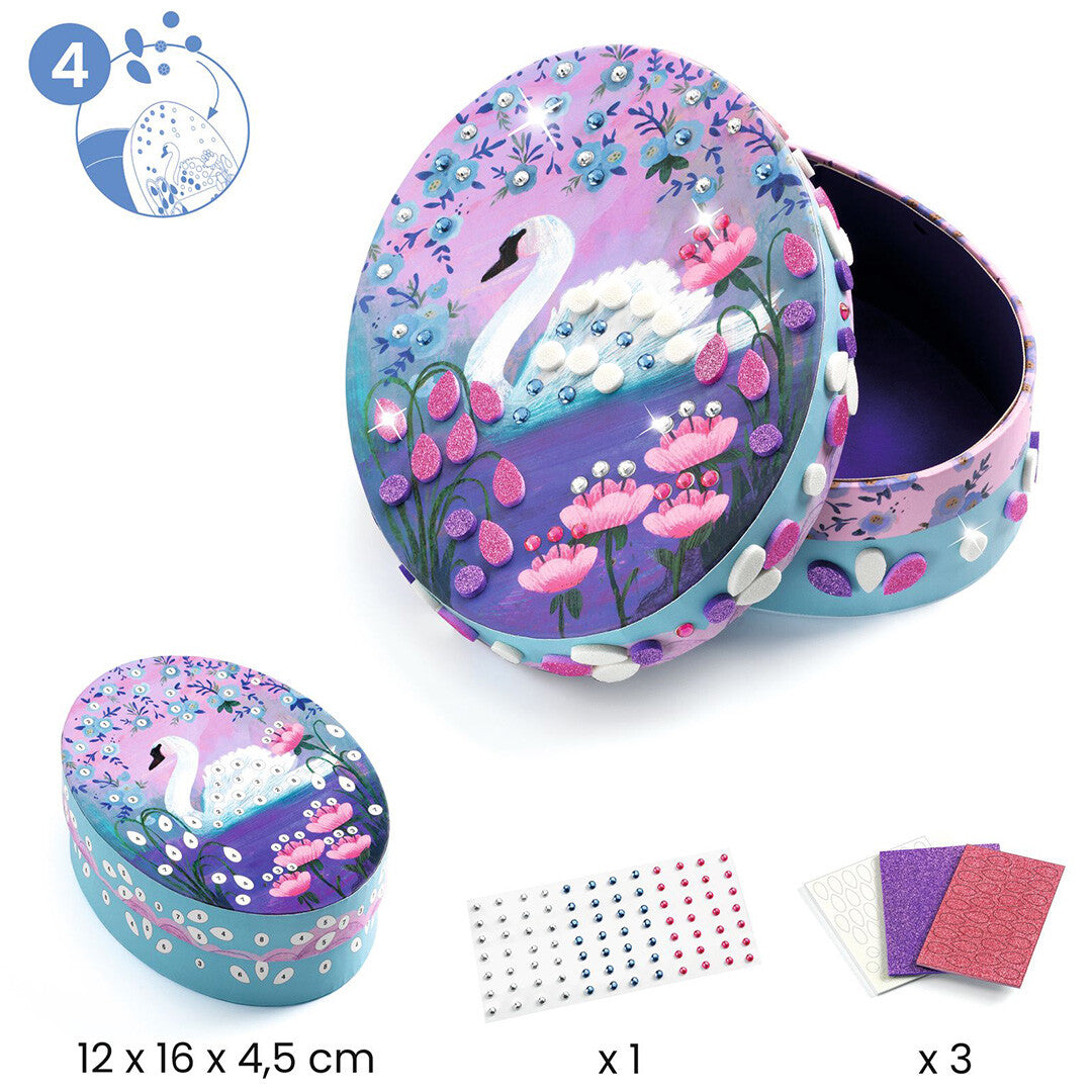 Infographic van een Djeco knutselset sieradendoosje met zwaan en bloemen, inclusief de benodigde materialen zoals edelstenen en glitterpapier.