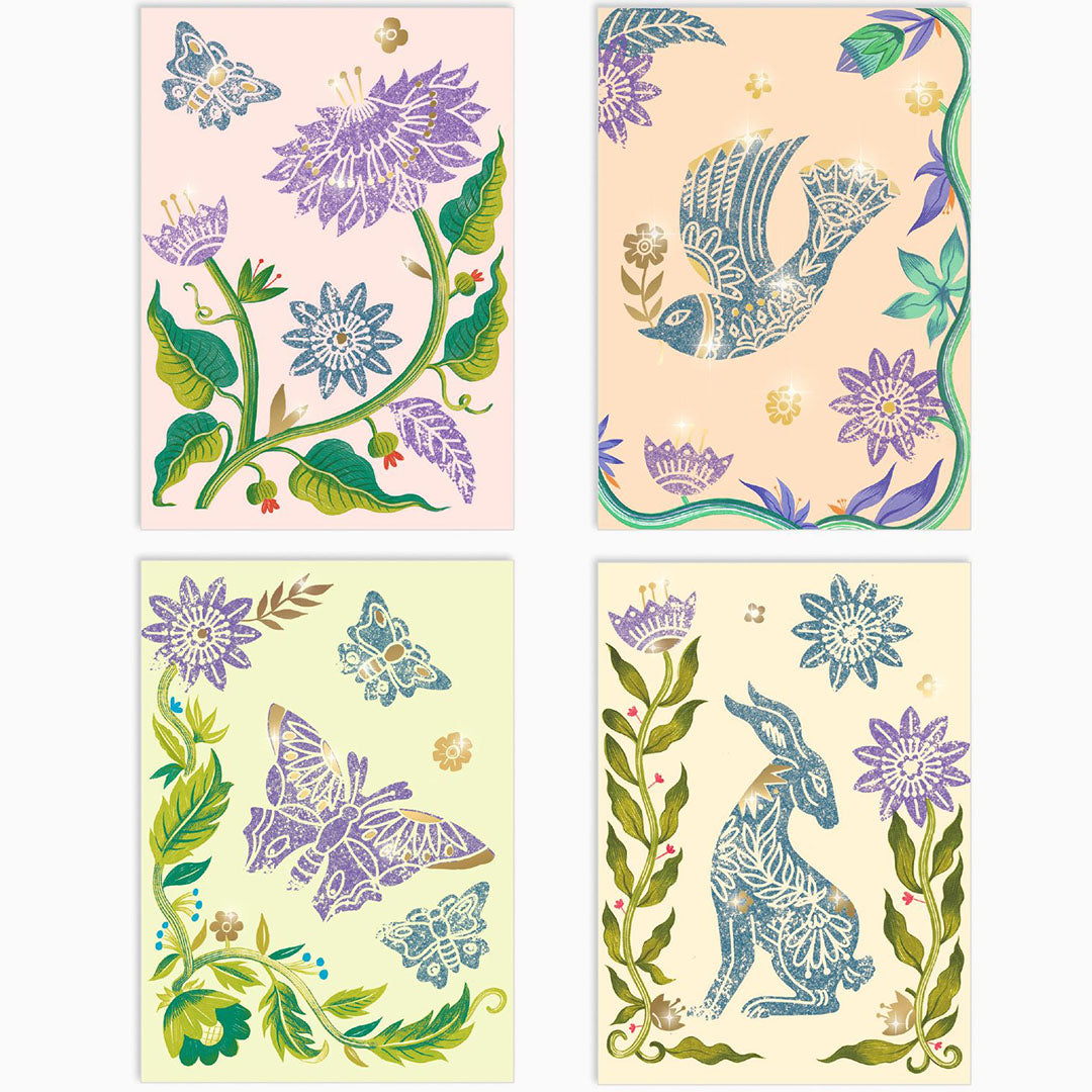 Vier afgewerkte knutselkaarten met glittergravures van bloemen, vlinders, een vogel en een konijn.
