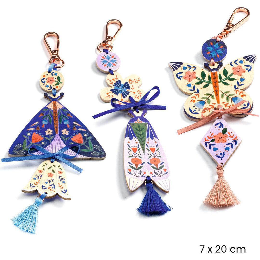 Drie gemaakte sleutelhangers met vlinder- en bloemmotieven, inclusief kwastjes en karabijnhaken.