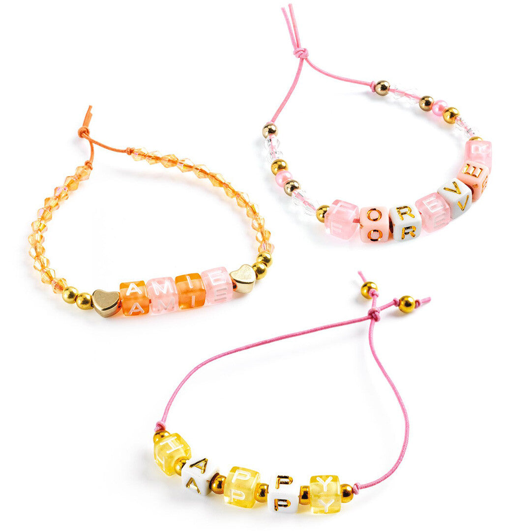 Drie gemaakte armbanden van de Djeco kralenset met letterkralen die de woorden 'AMIE', 'FOREVER' en 'HAPPY' spellen.