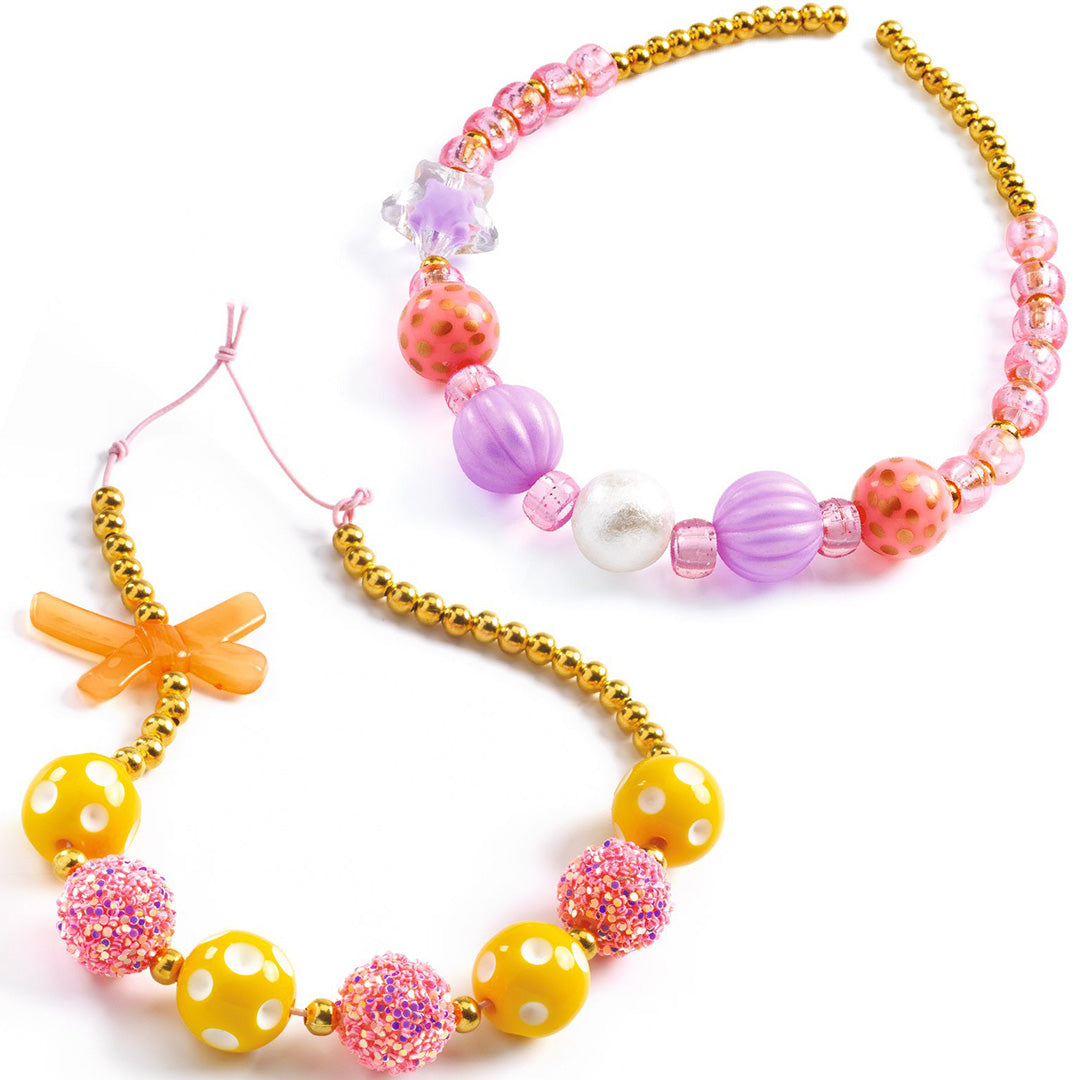 Twee gemaakte kettingen van de Djeco kralenset met roze, gele en paarse kralen en gouden accenten.