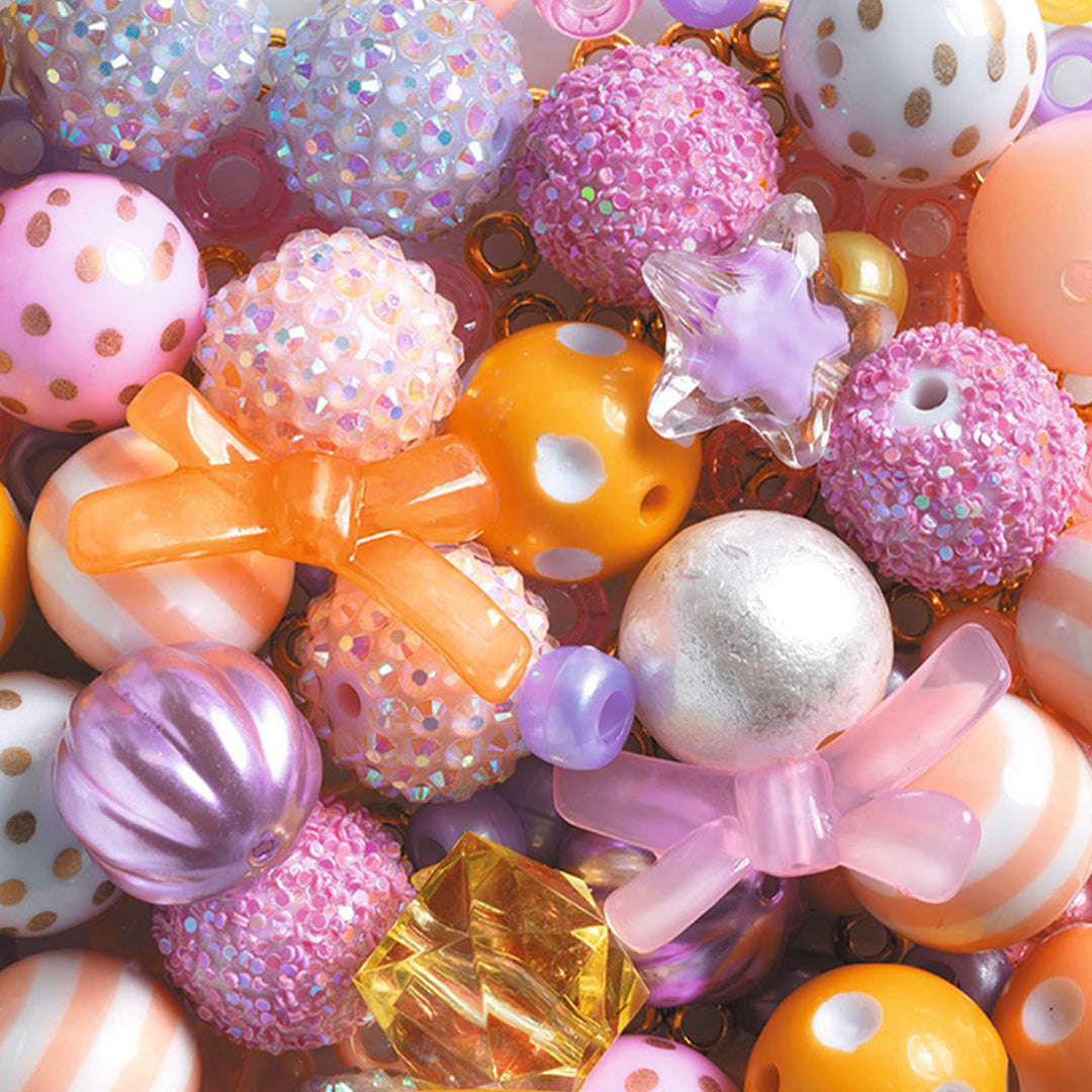 Detailopname van diverse kleurrijke kralen uit de Djeco kralenset, waaronder glitter-, stip- en strikkralen.