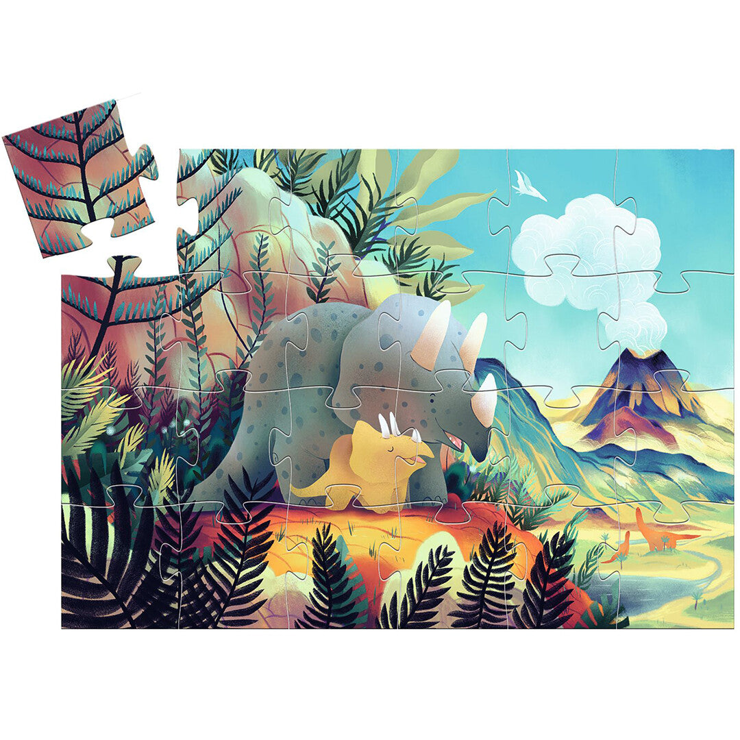 De Djeco legpuzzel van 24 stukjes met een grote en kleine triceratops in een prehistorisch landschap, met één los puzzelstukje.