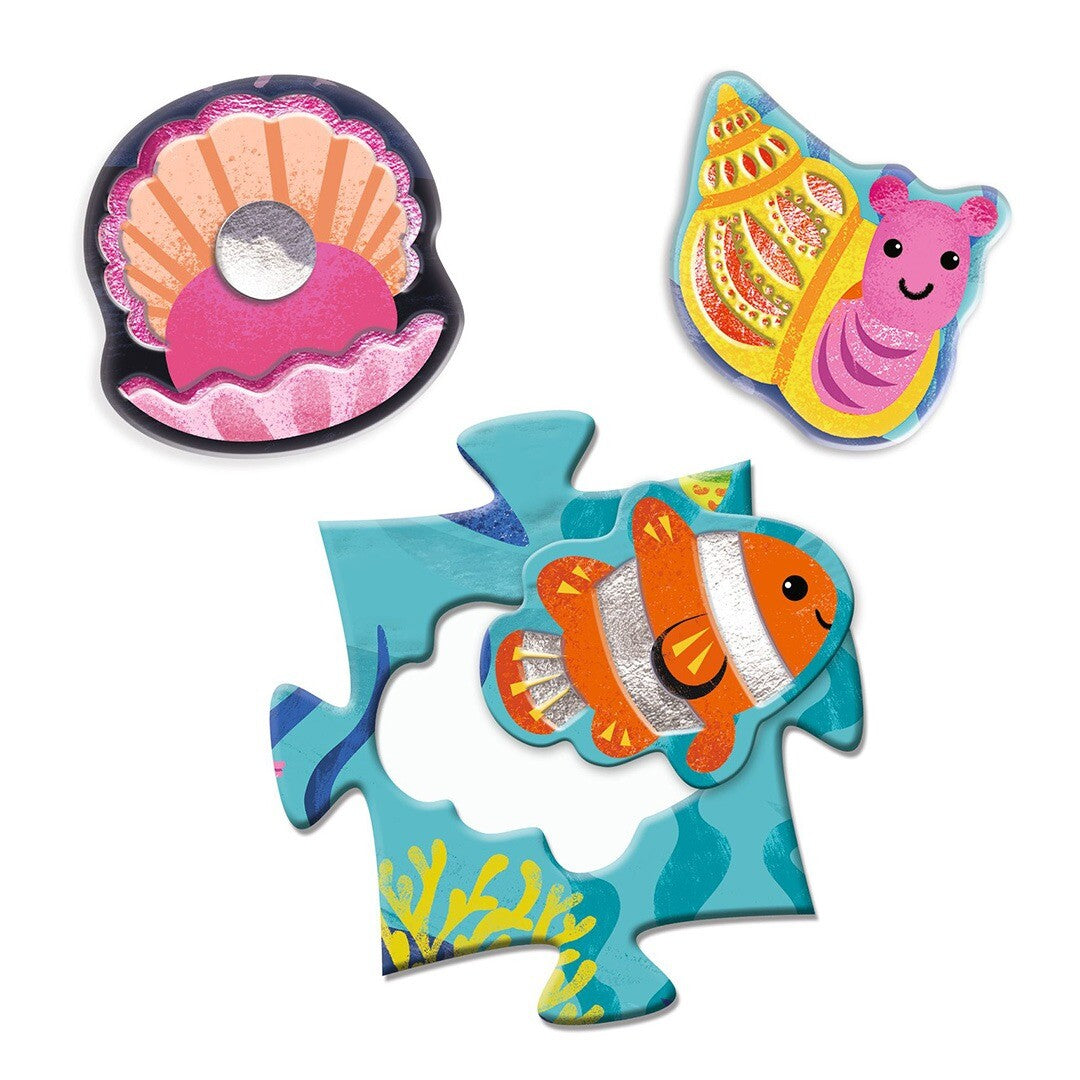 Drie losse puzzelstukken van de oceaan dieren legpuzzel, waaronder een clownvis en een parel.
