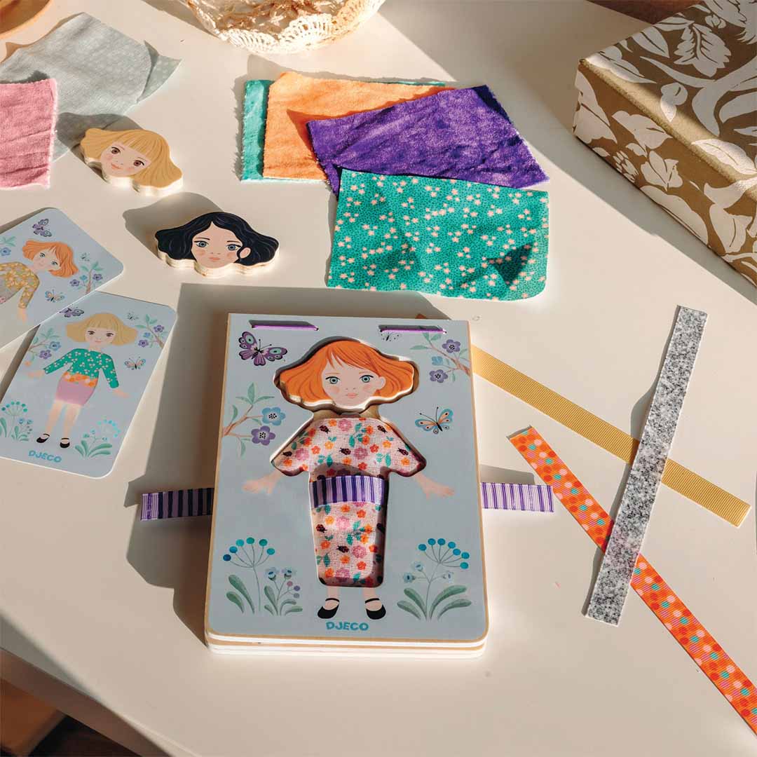 De Djeco Zabichic aankleedpop set met de houten pop, verschillende stoffen en papieren kledingstukken en extra hoofden.