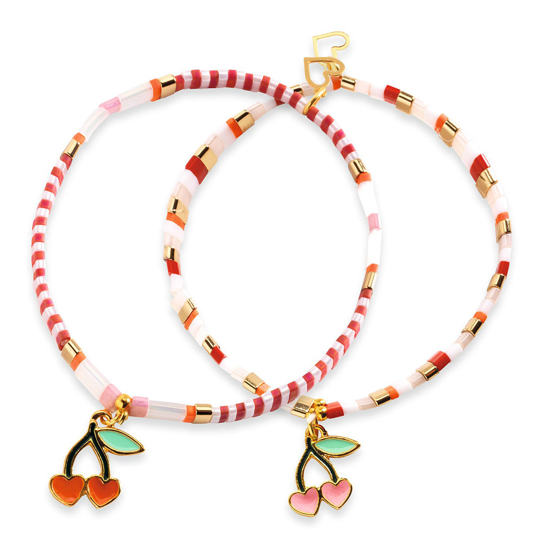 Twee afgewerkte kinderarmbandjes met gestreepte kralen en kersenbedeltjes.