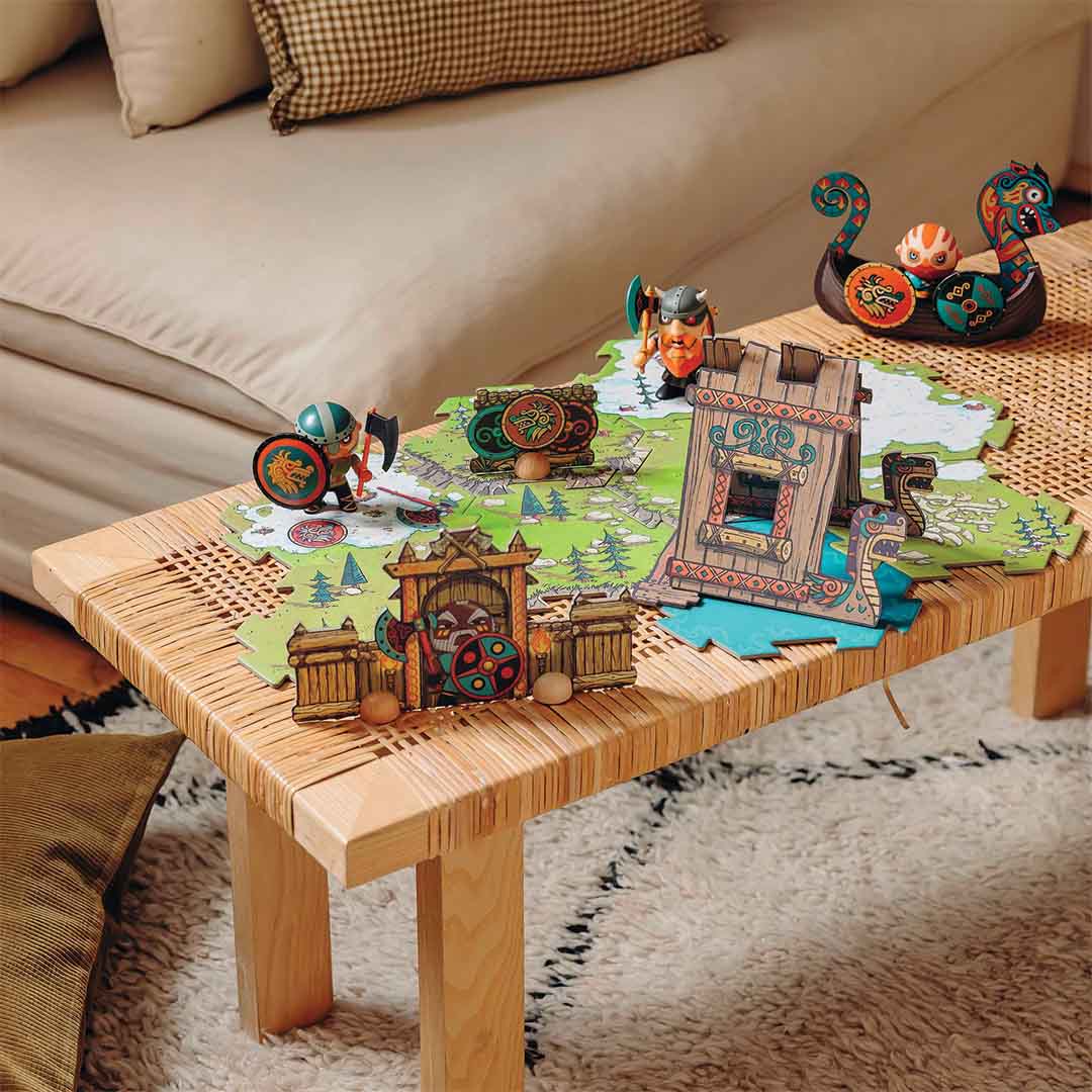 De Djeco Arty Toys Alric Barbarious vloerpuzzel met figuren en bouwwerken op een houten tafel.