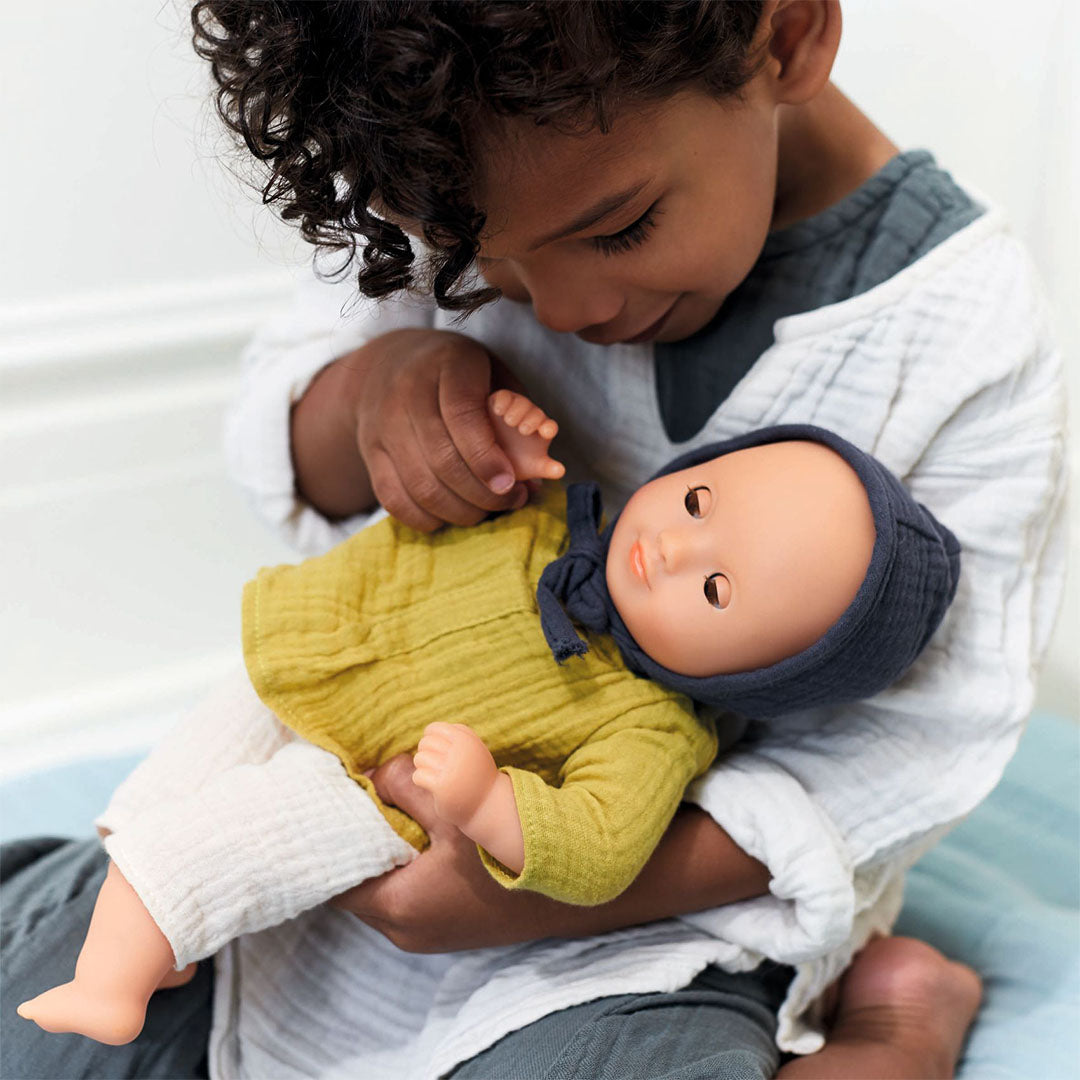 Een kind houdt de Djeco babypop Camomille vast en kijkt ernaar.