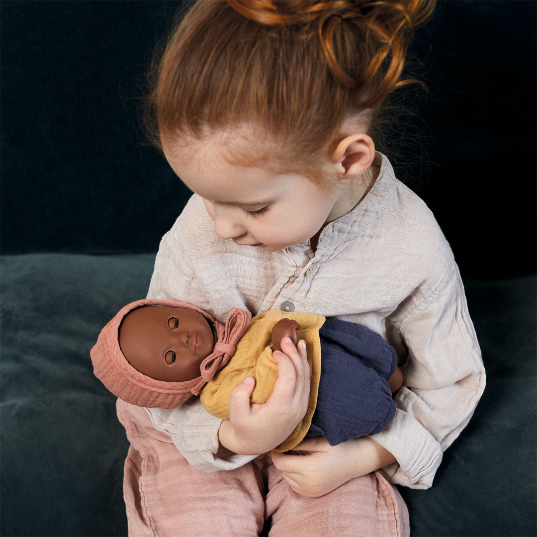 Een kind houdt de Djeco babypop Mimosa met gesloten ogen vast.
