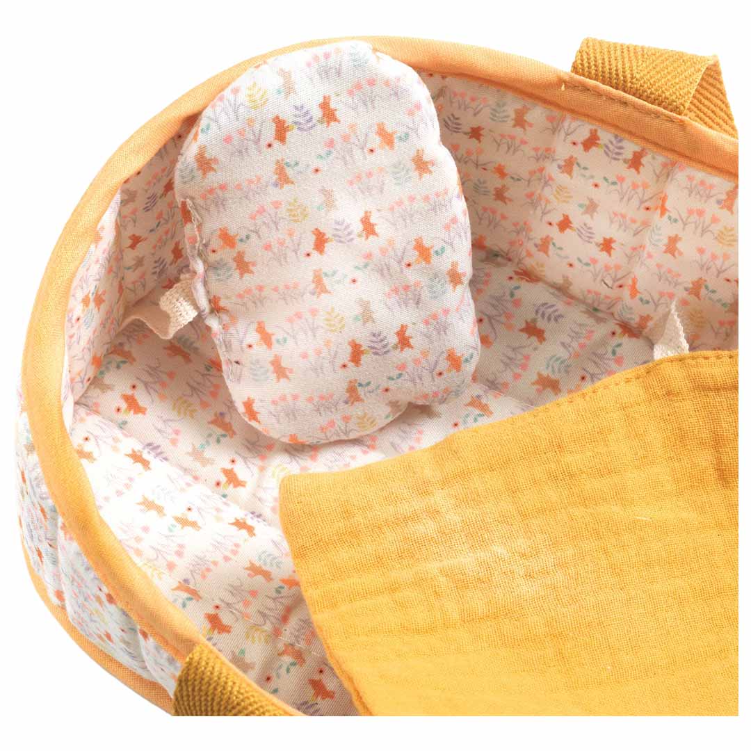 Detail van de Djeco Pomea draagmand met een patroon van dieren en bloemen en een geel dekentje.