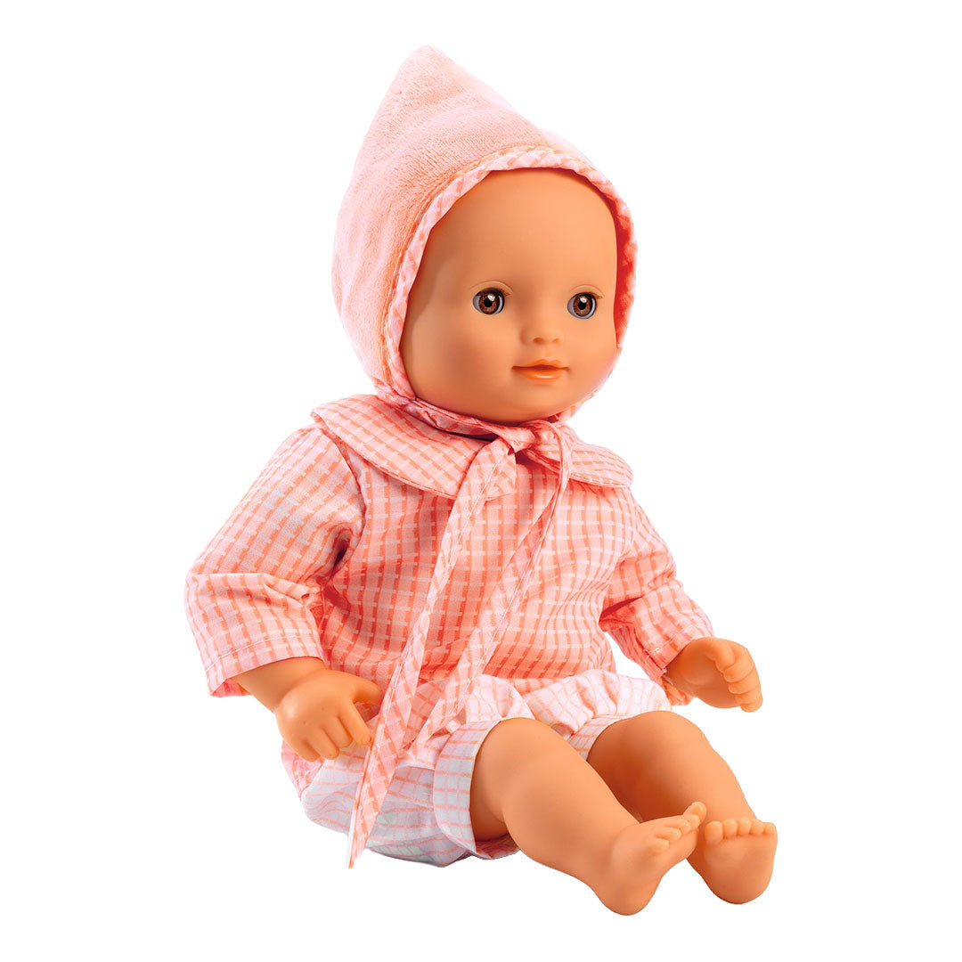 Djeco babypop Rose zittend in een roze geruit shirt met bijpassende muts.