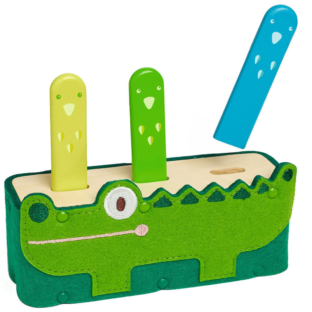 Djeco pop-up babyspeeltje in de vorm van een groene krokodil met drie gekleurde stokjes, waarvan er één omhoog springt.