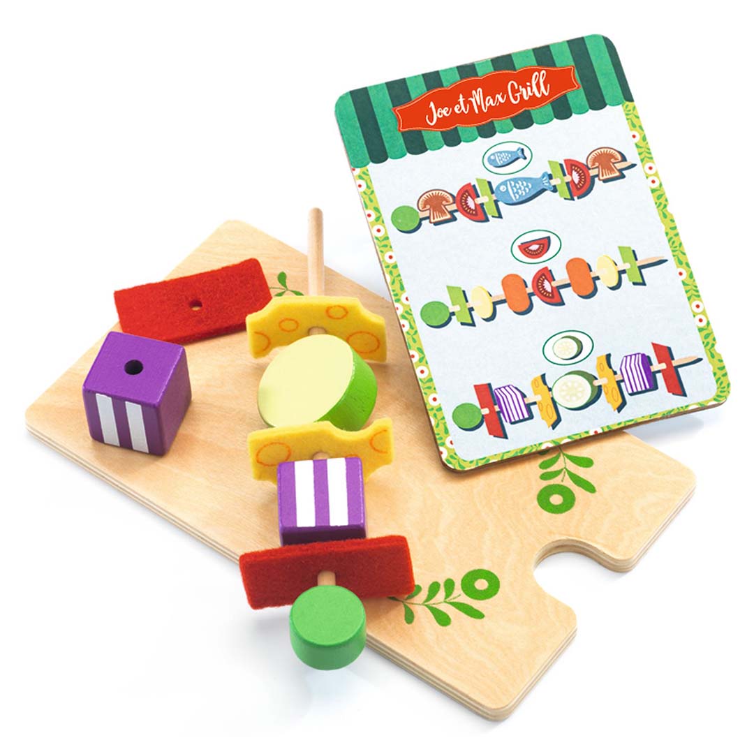 Detail van de Djeco barbecue speelset met een houten spies met diverse etenswaren en een receptenkaart.
