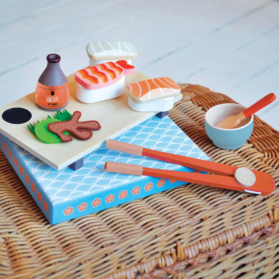 Djeco houten speelset met Japanse sushi, een serveerplank, eetstokjes en een kommetje op een rieten ondergrond.