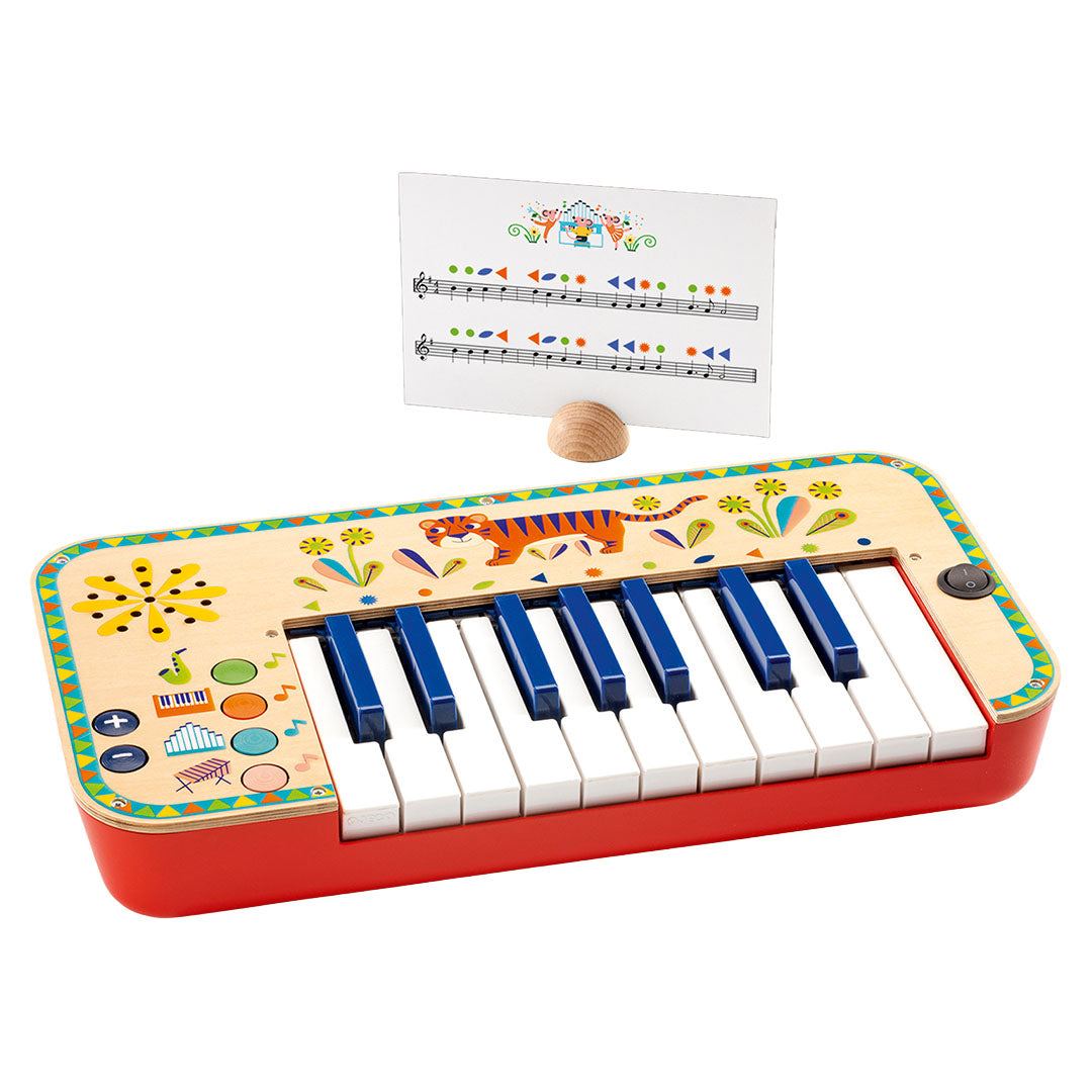 Djeco elektrisch keyboard Animambo met rode basis, houten bovenkant met dieren- en bloemenpatronen, en een muziekstandaard met bladmuziek.