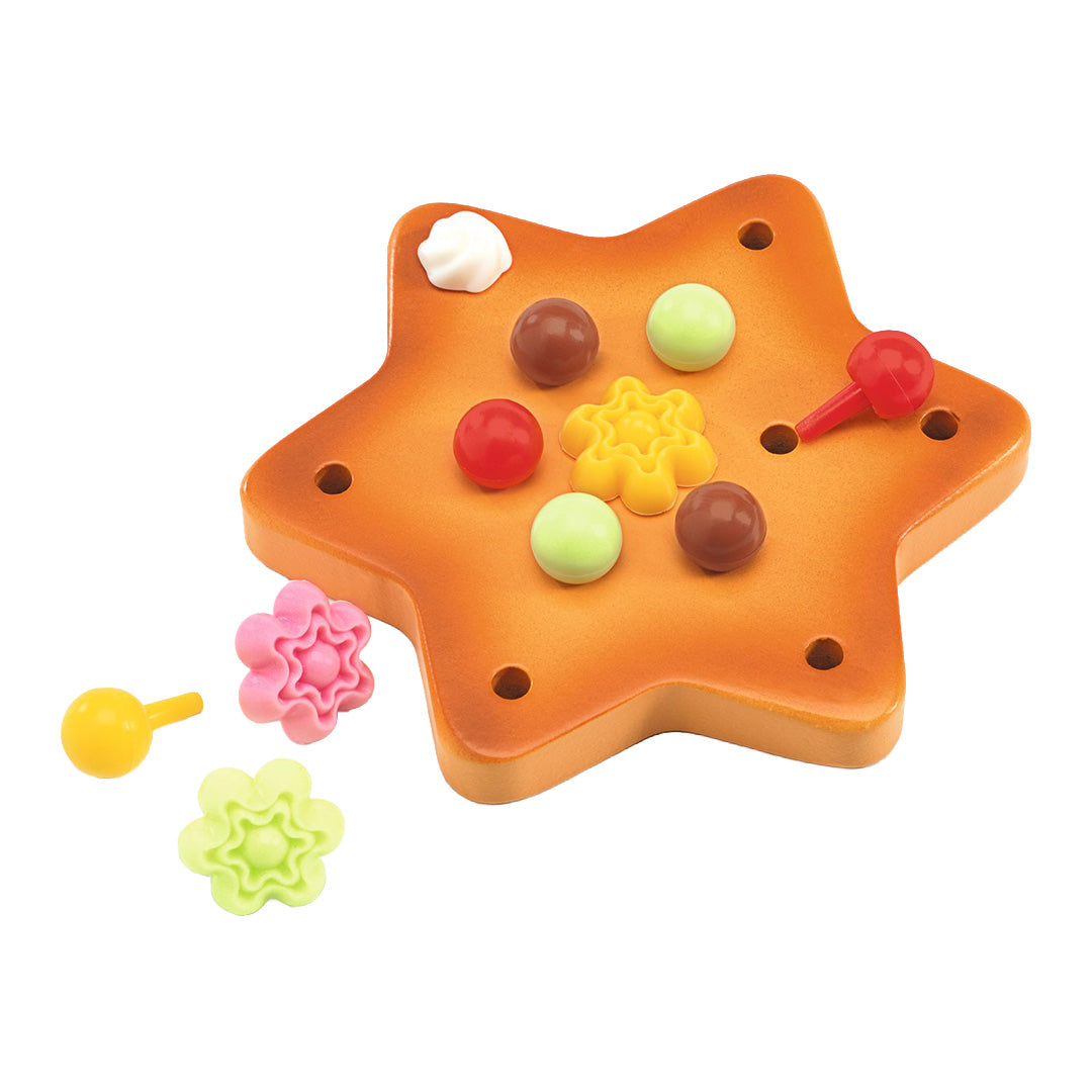 Een oranje stervormig speelgoedkoekje met diverse kleurrijke decoraties erop en ernaast.