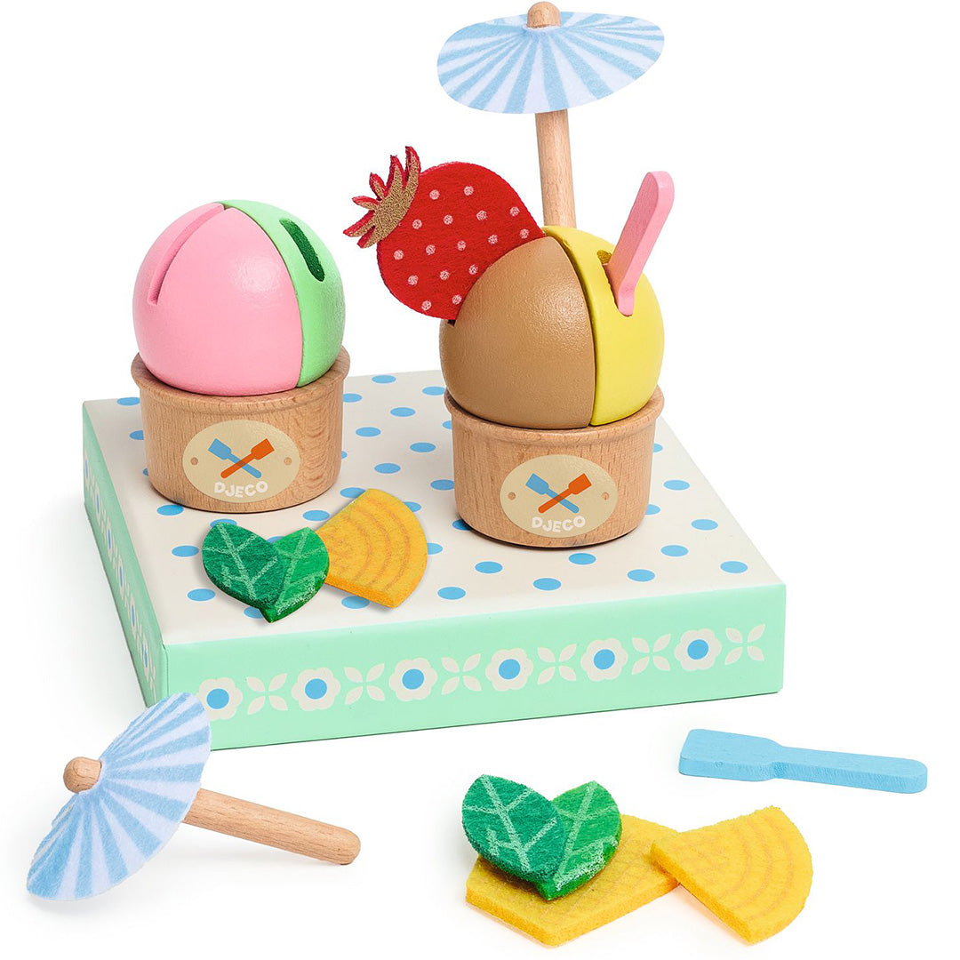 Djeco houten speelgoedijsjes in bakjes met toppings, een parasolletje en een ijsschep op een gestippelde ondergrond.