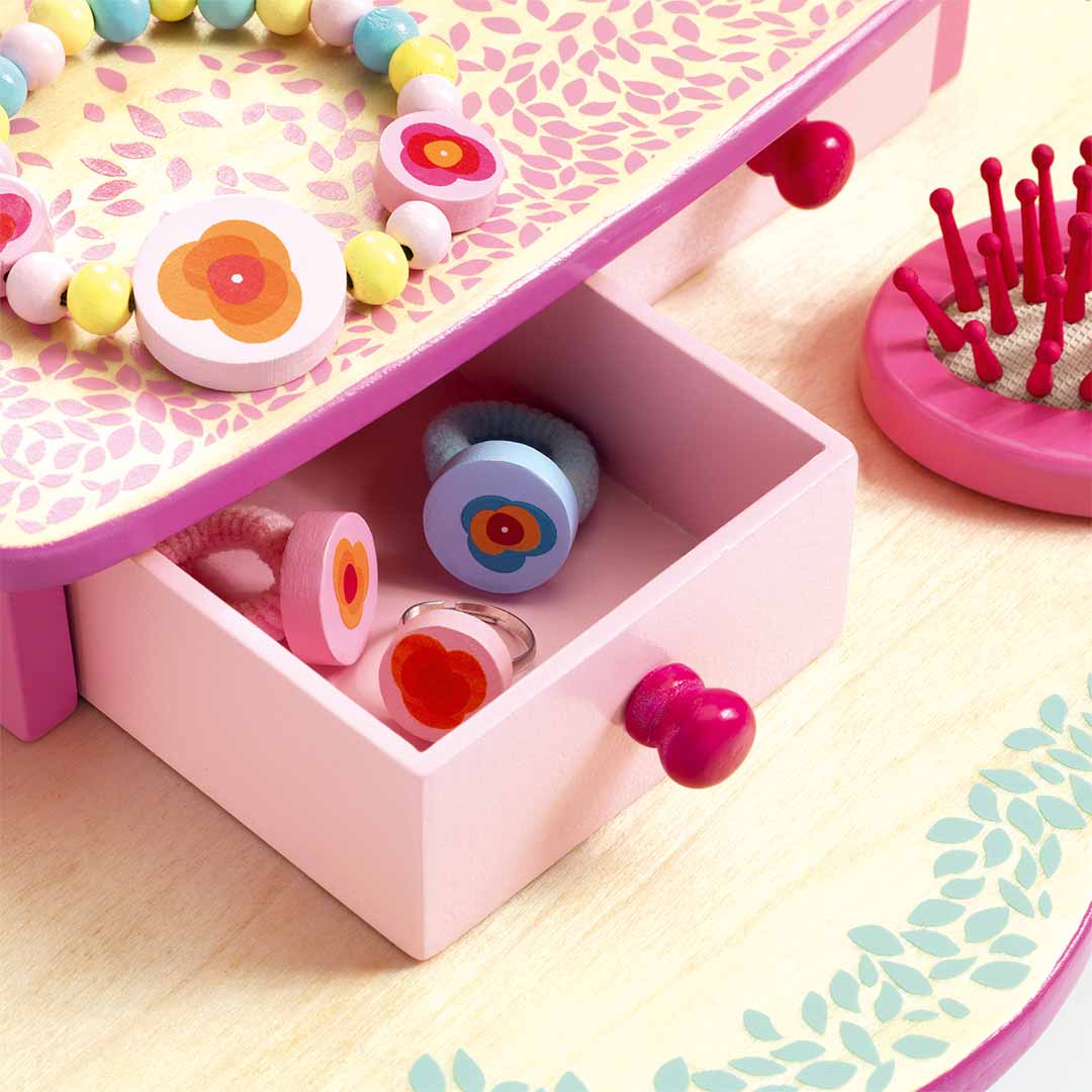 Detail van het Djeco houten kaptafeltje Flora met een open lade vol speelgoedringen en haarelastiekjes.