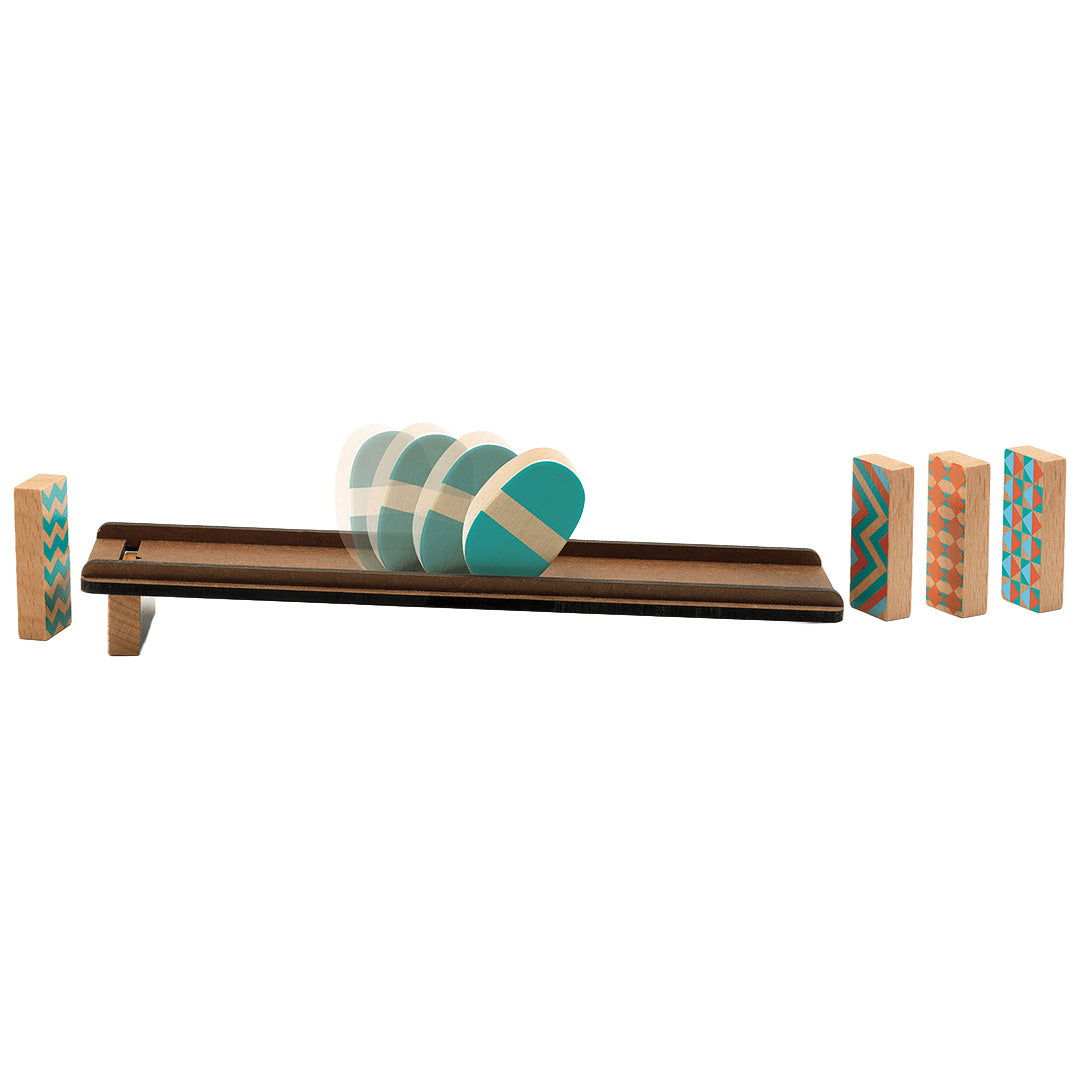 Het Djeco kettingreactiespel in actie, met een houten culbuto die over een baan rolt richting blokken met geometrische patronen.