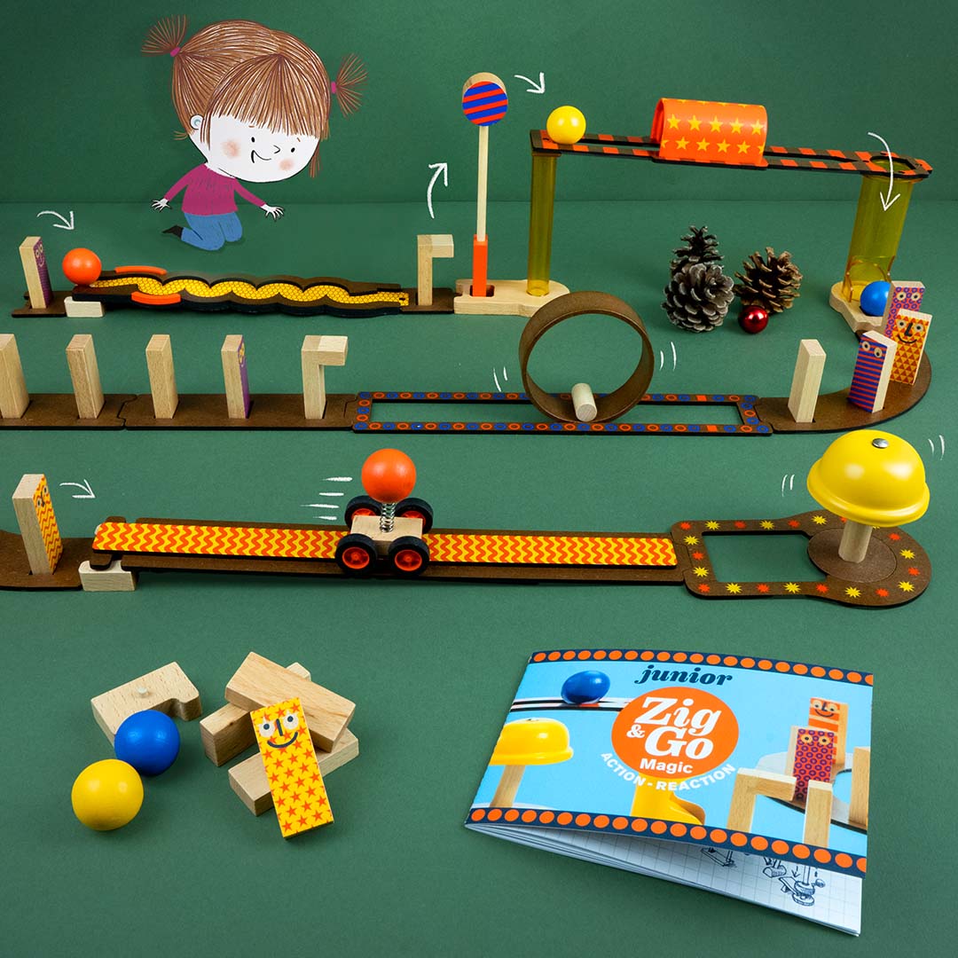 Het Djeco Zig & Go Junior kettingreactiespel op een groene ondergrond met een instructieboekje en decoratie.