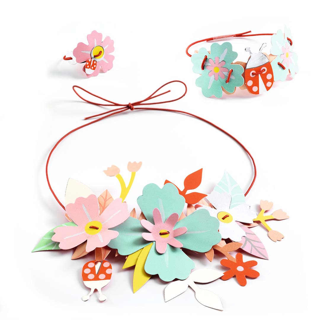 Drie gemaakte sieraden van de Djeco knutselset: een ketting, armband en ring met bloemen, bladeren en lieveheersbeestjes.