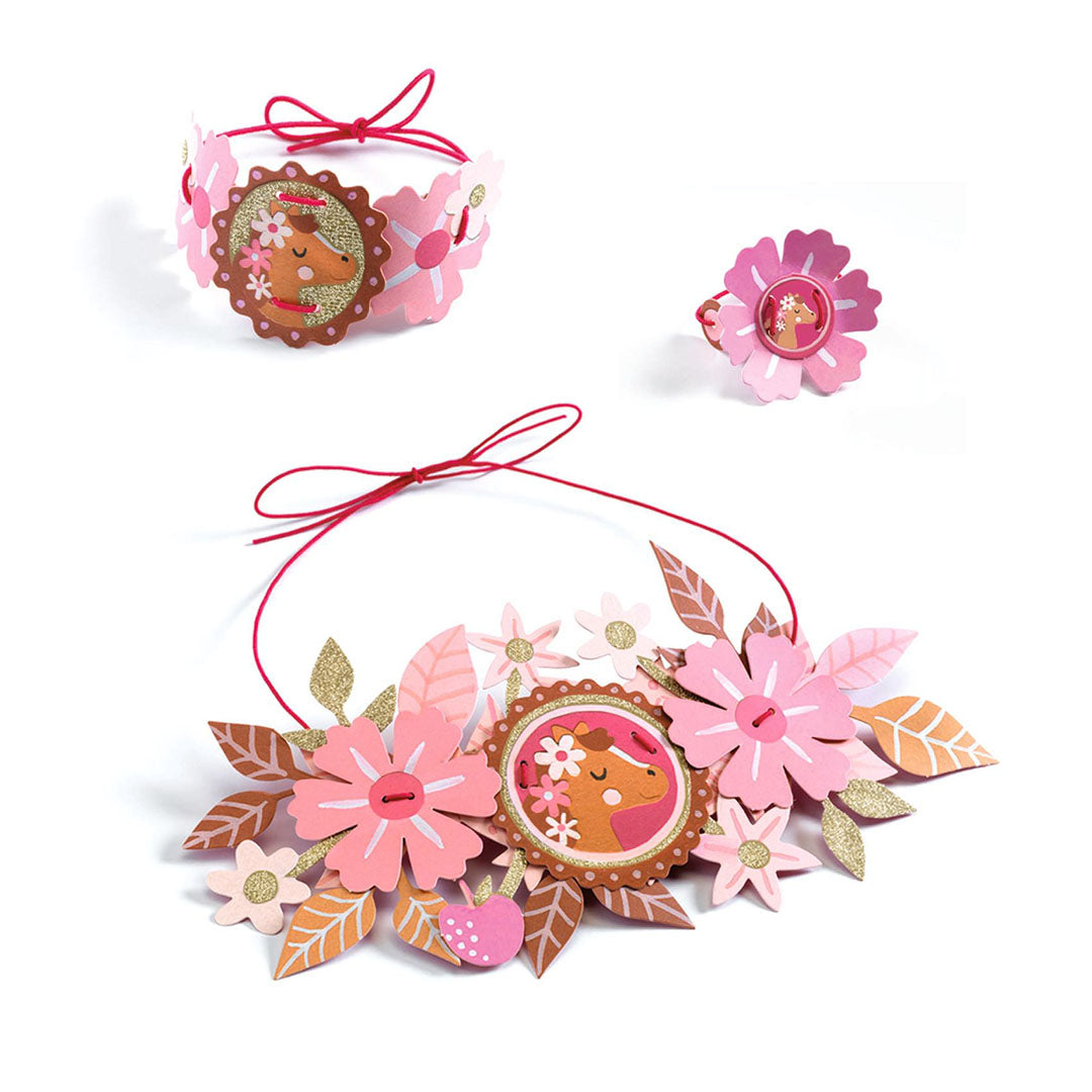 Een set van roze bloemen sieraden met een paardenmotief, bestaande uit een ketting, armband en ring.