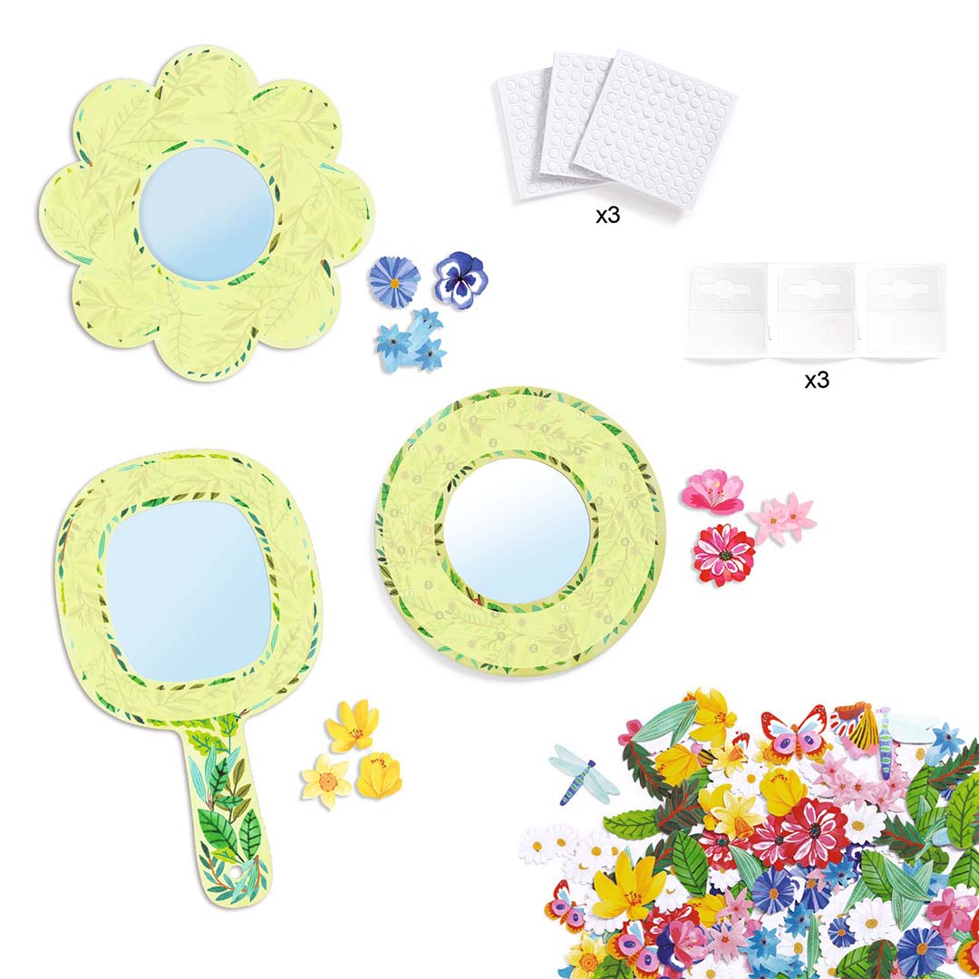 De losse onderdelen van de knutselset, met drie onversierde spiegelvormen en stapels papieren bloemen, vlinders en libellen.