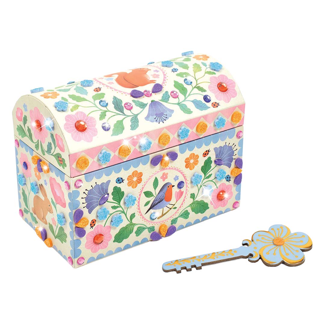 Een versierde schatkist met bloemen, vogels en glimmende steentjes, naast een bijpassende decoratieve sleutel.